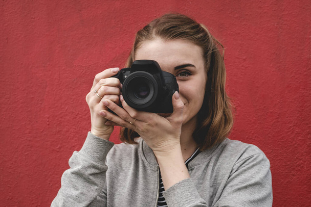 Fiatal nő áll a szabadban fényképezés színes piros fal - Fotó, kép