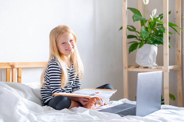 Distance learning online education. Schoolboy and girl studying at home with digital tablet laptop notebook and doing school homework. Sitting on bed with training books. - Valokuva, kuva
