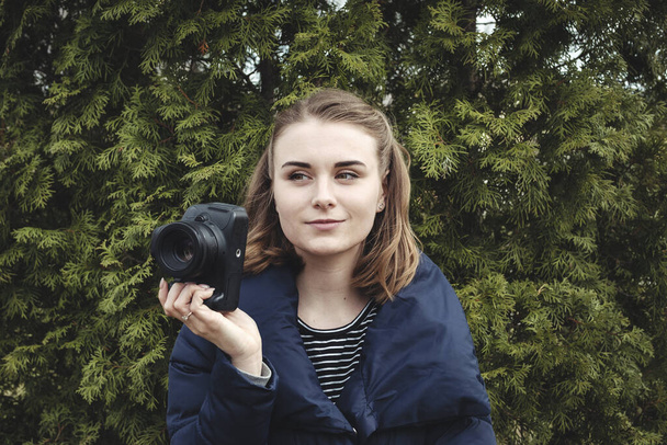 Attractive smiling photographer holding her camera in one hand - Photo, Image