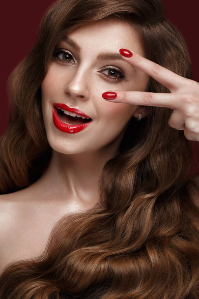 Menina bonita com uma maquiagem clássica, cabelos cachos e unhas vermelhas. Design de manicure. Cara de beleza
. - Foto, Imagem