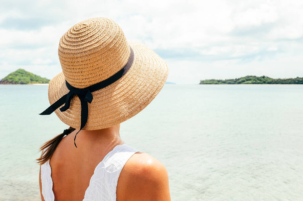 Woman in summer vacation wearing straw hat enjoying the view at the ocean - Fotografie, Obrázek