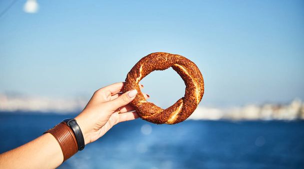 Simitci- un tradizionale bagel turco rotondo con semi di sesamo in mano sullo sfondo del Mar di Marmara e del paesaggio urbano di Istanbul
 - Foto, immagini