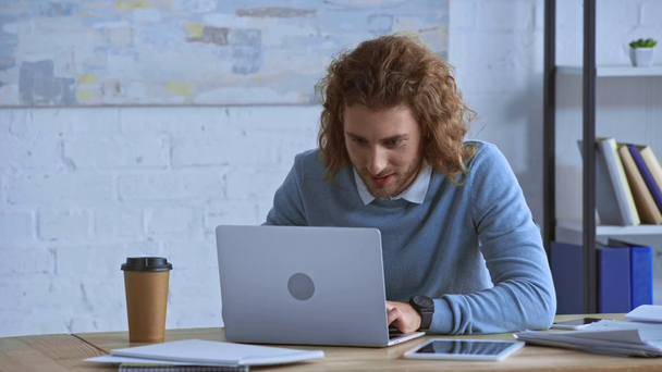 heureux bouclé homme d'affaires en utilisant un ordinateur portable au bureau
  - Séquence, vidéo