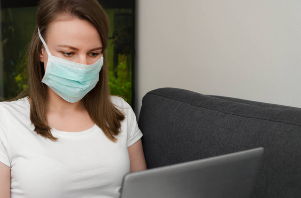 Woman in medical mask working from home. Isolation at home. - Valokuva, kuva