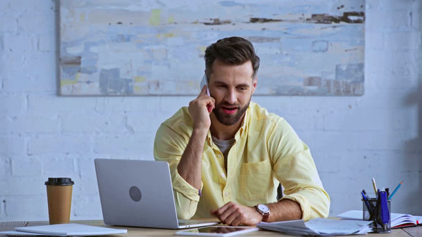 happy and bearded man talking on smartphone in office  - Felvétel, videó