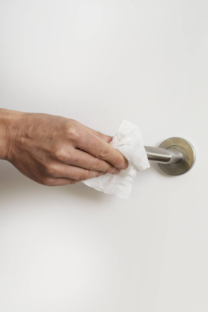 primer plano de un hombre caucásico limpiando la manija de la puerta con una toallita desinfectante
 - Foto, imagen