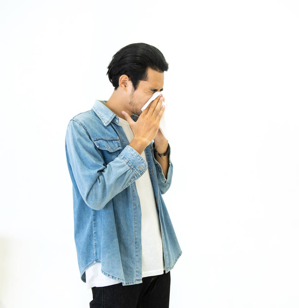 Junger asiatischer gutaussehender Mann in lässigem Jeanskleid mit Grippesaison und Niesen mit Papiertaschentüchern verhindert die Ausbreitung von Viren und Bakterien isoliert auf weißem Hintergrund, Gesundheits- und Krankheitskonzepte - Foto, Bild