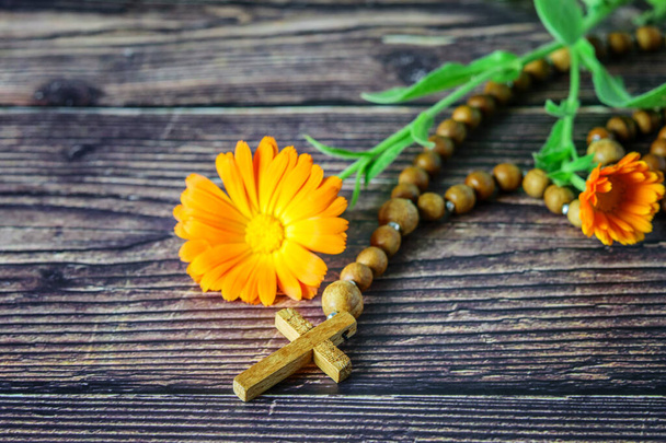 Ξύλινο χριστιανικό σταυρό με ξωκλήσι και ένα λουλούδι στο φόντο του ξύλου closeup. Χριστιανική θρησκεία έννοια, Πάσχα.  - Φωτογραφία, εικόνα