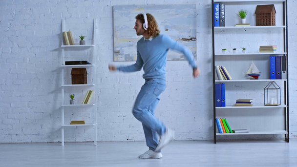 щасливий чоловік в бездротових навушниках танцює в офісі
  - Кадри, відео