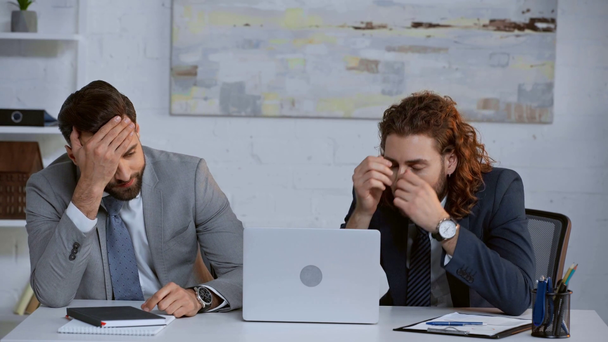 displeased businessmen in suits near laptop  - Кадри, відео