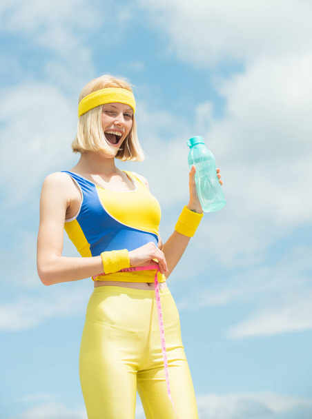 Fitness woman. Woman winking and holding water. Woman stomach. Young girl doing body measurements. - Foto, Bild
