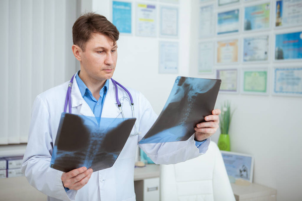 Врач-мужчина осматривает два рентгеновских снимка пациента. Опытный врач, работающий в клинике
 - Фото, изображение