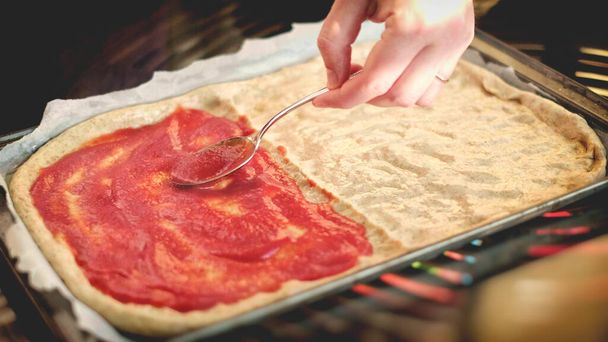  руки розкладають томатне пюре з ложкою на листі бака - домашня сільська піца італійський кулінарний фон
 - Фото, зображення