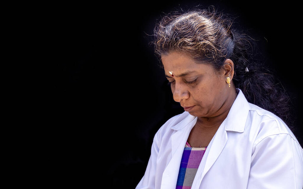 Een close-up foto van een arts die neerkijkt op het uniform op een zwarte achtergrond - Foto, afbeelding