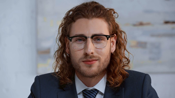 happy and curly businessman in glasses looking at camera - Séquence, vidéo