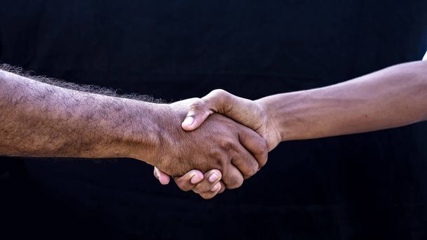 people concepts. Two men shaking hands isolated on black backgrounds - Foto, afbeelding