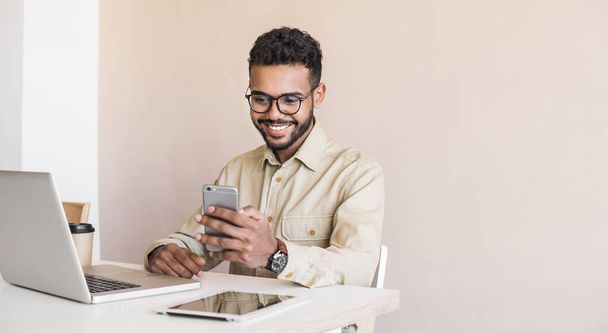 young handsome man working in office with smartphone - Foto, afbeelding