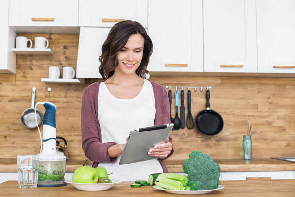 Young beautiful woman using tablet while cooking  - Photo, Image