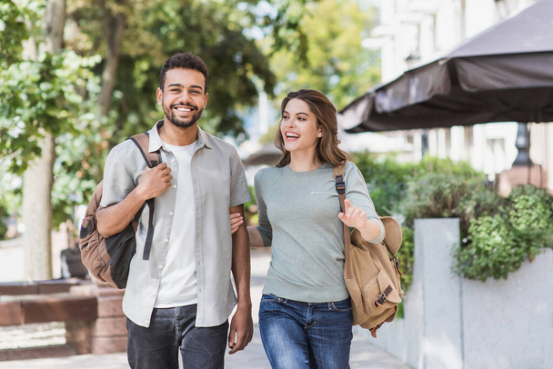 Beautiful happy tourists couple summer portrait, young cheerful smiling woman and man walking in city, love, travel, tourism, students concept - 写真・画像