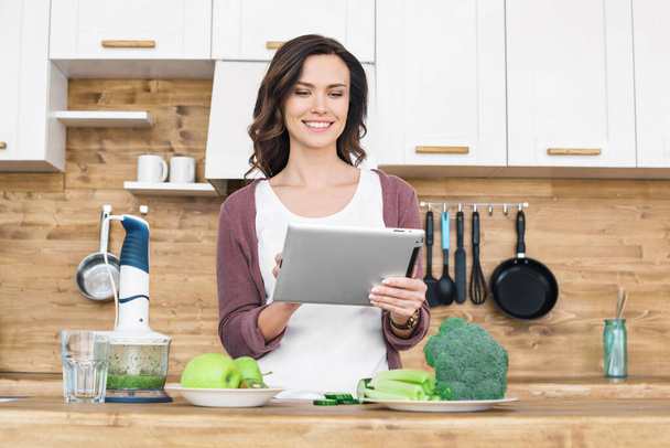 Young beautiful woman using tablet while cooking  - 写真・画像