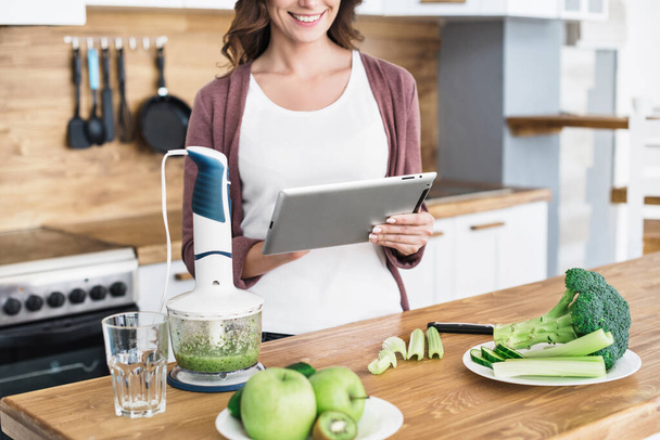 Young woman preparing food, making smoothie and exploring new recipe using digital tablet, cooking and healthy eating concept - Фото, зображення