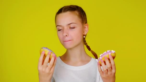 Adolescente ragazza in una t-shirt bianca guarda ciambelle e vuole mangiarle
 - Filmati, video