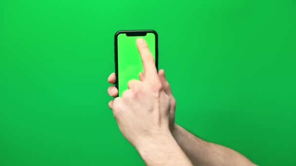 Τηλέφωνο στο χέρι απομονώνονται σε ένα πράσινο φόντο. Οθόνη τηλεφώνου - πράσινο chroma κλειδί, φόντο πράσινο chroma κλειδί. Πλαίσια για κινητές διαφημίσεις, διαφημιστικά μηνύματα. - Πλάνα, βίντεο