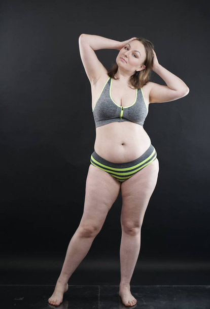 plus size woman shows her body in stretch marks and hair with cellulite and encourages you to love and accept yourself in any way . black background in the Studio. full length photo - Fotografie, Obrázek