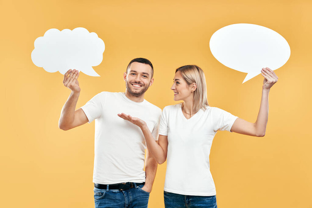 Woman and man holding paper thought bubbles over yellow background.  - Foto, Imagem