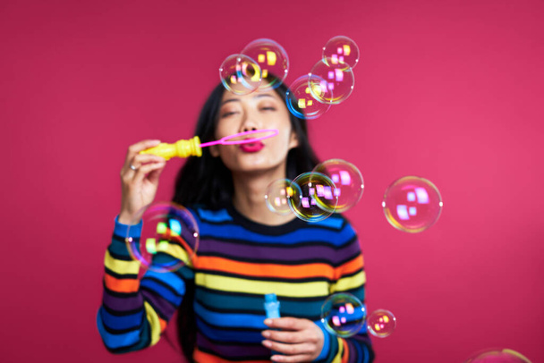 Happy beautiful woman blowing soap bubbles isolated over pink background                    - Foto, Bild