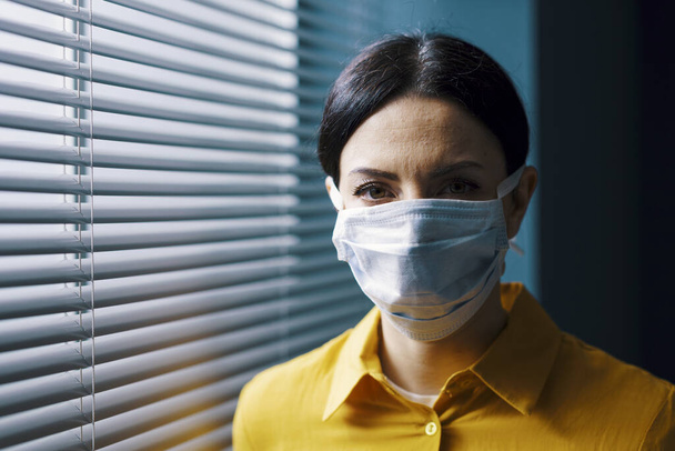 Woman wearing a surgical mask and looking at camera, covid-19 outbreak and virus contagion concept - Foto, immagini