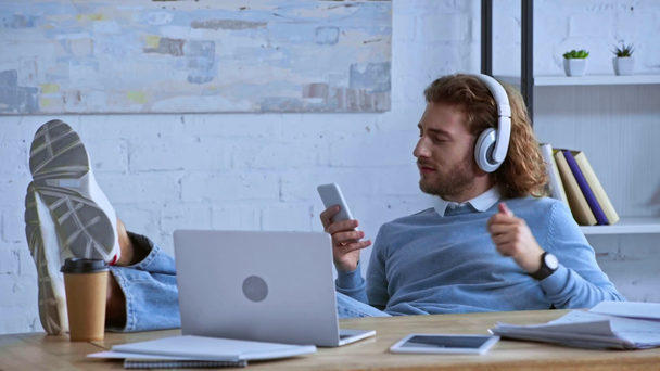 happy businessman listening music in headphones near laptop  - Πλάνα, βίντεο
