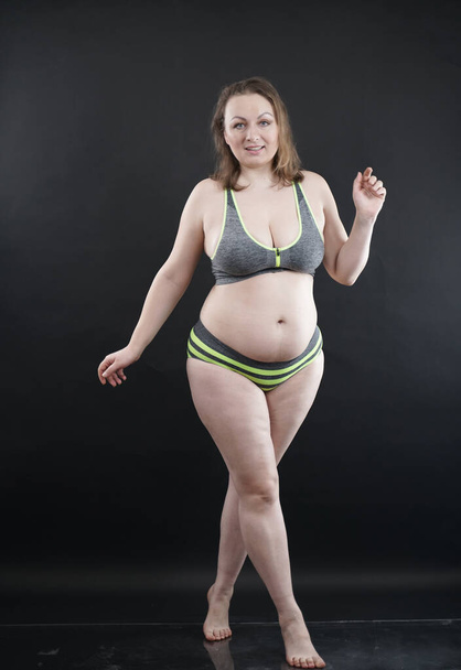 plus size woman shows her body in stretch marks and hair with cellulite and encourages you to love and accept yourself in any way . black background in the Studio. full length photo - Photo, image