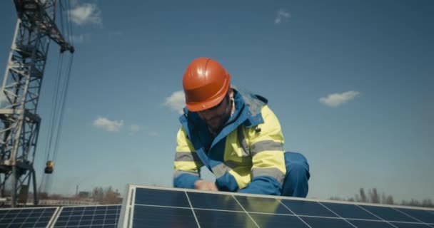 Technician installing solar panel and looking at camera - Filmati, video