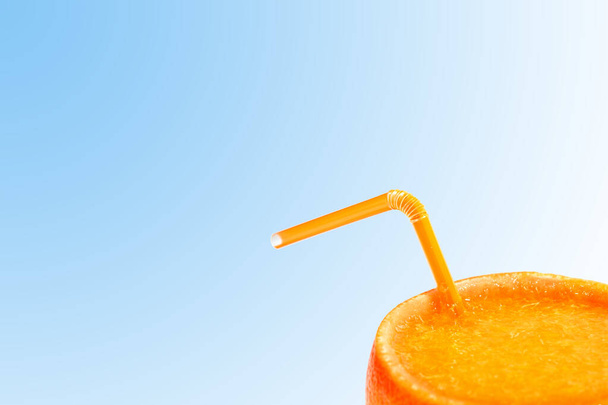 orange juice in the skin of an orange with a tube on the blue . concept of natural juices - Fotografie, Obrázek