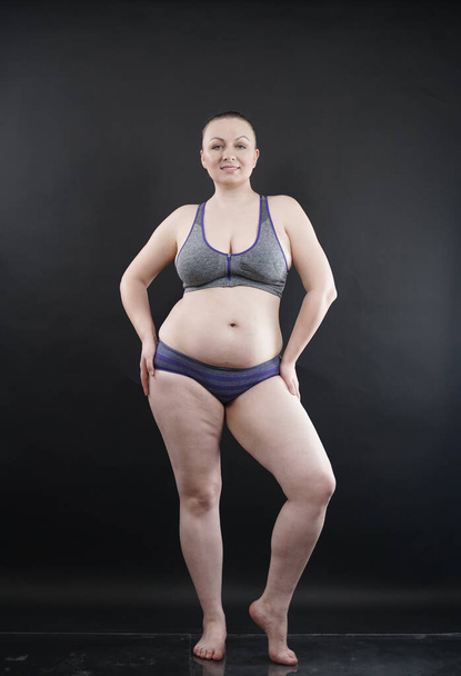 plus size woman shows her body in stretch marks and hair with cellulite and encourages you to love and accept yourself in any way . black background in the Studio. full length photo - Photo, Image