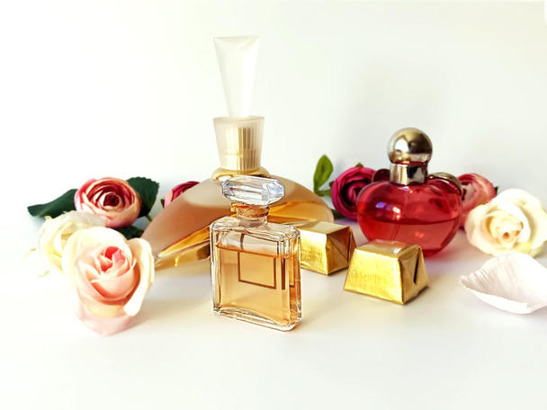 Parfümflasche Parfüm rot gelbes Glas mit Blütenblatt auf weißem Gold Hintergrund, Frauen Accessoires floralen Hintergrund, Kopierraum  - Foto, Bild