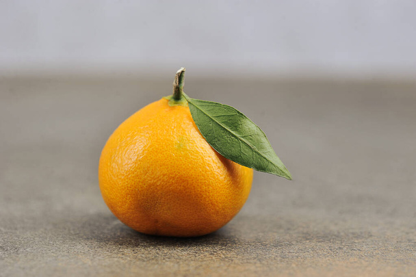 one ripe tangerine - whole tangerine with leave - close up - Zdjęcie, obraz