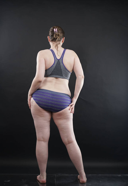 plus size woman shows her body in stretch marks and hair with cellulite and encourages you to love and accept yourself in any way . black background in the Studio. full length photo - Fotó, kép