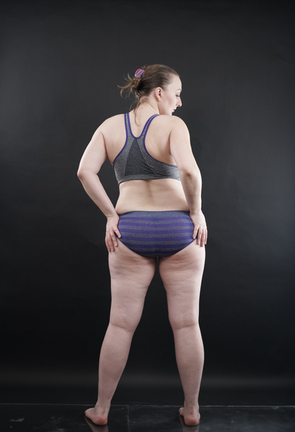 plus size woman shows her body in stretch marks and hair with cellulite and encourages you to love and accept yourself in any way . black background in the Studio. full length photo - Foto, Imagen