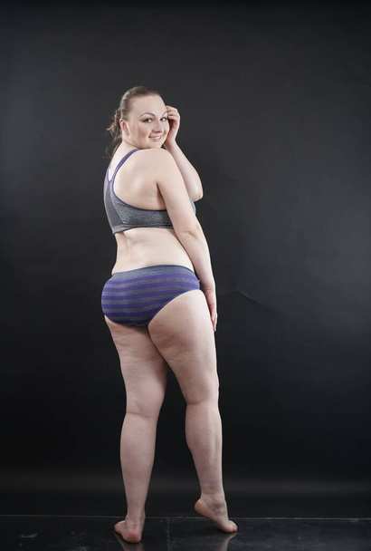 plus size woman shows her body in stretch marks and hair with cellulite and encourages you to love and accept yourself in any way . black background in the Studio. full length photo - Фото, зображення