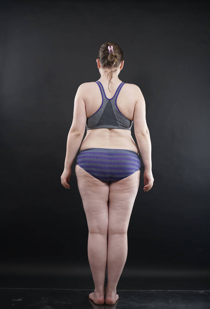 plus size woman shows her body in stretch marks and hair with cellulite and encourages you to love and accept yourself in any way . black background in the Studio. full length photo - Foto, imagen