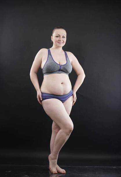 plus size woman shows her body in stretch marks and hair with cellulite and encourages you to love and accept yourself in any way . black background in the Studio. full length photo - Foto, imagen