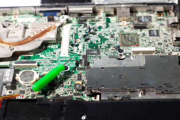 repairing a broken laptop, unscrewing screws with small screwdrivers. equipment repair shop - Photo, image