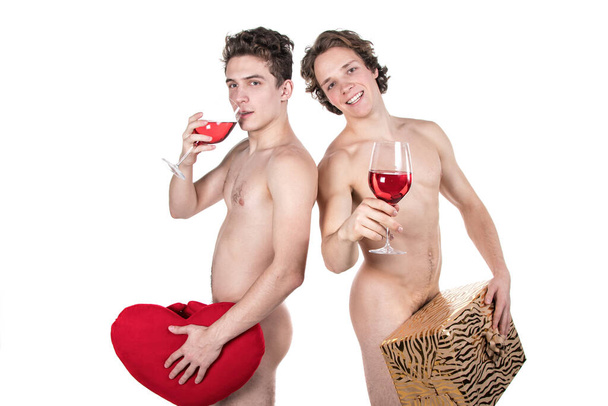 Two funny naked guys holding glasses with red wine and heart isolated on white - 写真・画像