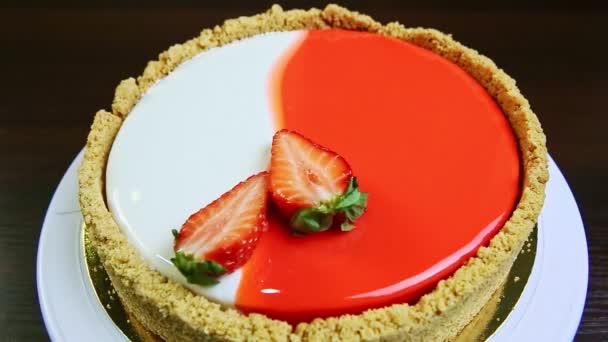 vrchní pohled detailní záběr celý kulatý glazovaný tvarohový koláč zdobený krájenými jahodami - Záběry, video