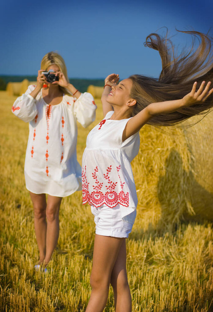 trente-cinq ans femme photographies long cheveux adolescent fille dans un champ près d'une meule de foin
 - Photo, image