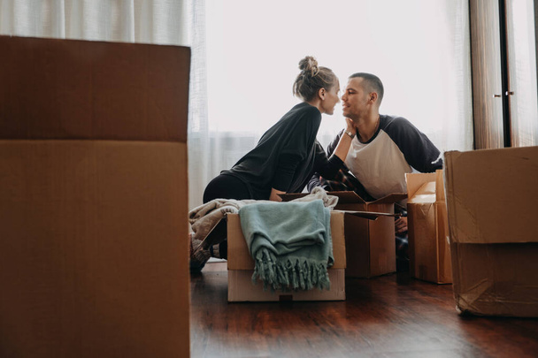 Moving Day, new home, Valentine's Day, unpacking boxes, newlyweds concept. Happy couple is having fun with cardboard boxes in new house. - Fotó, kép
