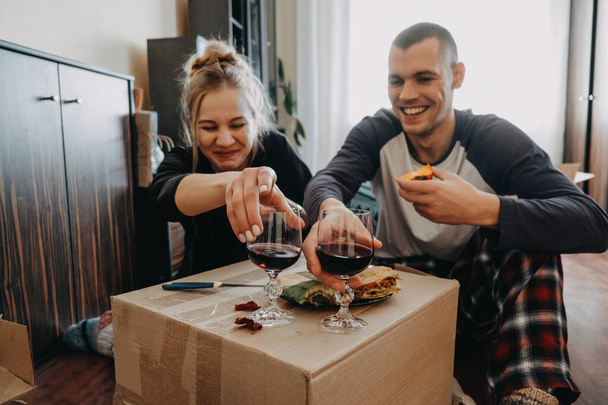 Moving Day, new home, Valentine's Day, unpacking boxes, newlyweds concept. Couple Celebrating Moving Into New Home With wine. - Φωτογραφία, εικόνα