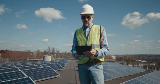 Engineer using tablet between solar panels - Кадри, відео